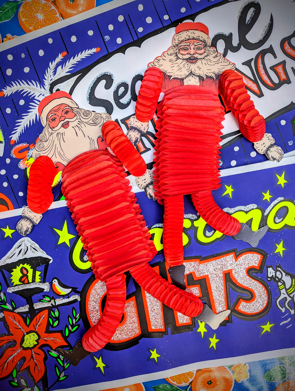 Completely nuts , gorgeous American vintage, 1960s  style Santa's with tissue arms and legs that dance in the slightest breeze!!  Hang up for Christmas displays, windows and decorations, these are soooooo hilarious

Pack of 2

53 cm long

Made of printed card and tissue, printed both sides.

 