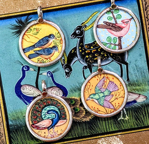 Free flying birds symbolising beauty,  grace, freedom, peace and as messangers between the divine and earth.
Made in Rajasthan, these pendants are crafted from sterling silver, glass and hand painted images on paper. The fine craftsmanship in these paintings is mind blowing, painting with single paint brush bristles!!!

These pendants should be removed when washing/swimming etc as they are in effect framed pieces of art, that although sealed are not water tight! 
Size 25mm diameter and 7mm loop.
