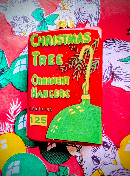  Gorgeous and bonkers faux vintage box of bauble hangars,  based on vintage American Christmas packaging artwork 💖

Hand made, painted and glittered for pure joy!!

Size 7cm x 4.5cm x 2cm

Glass.
Cody Foster & Co 