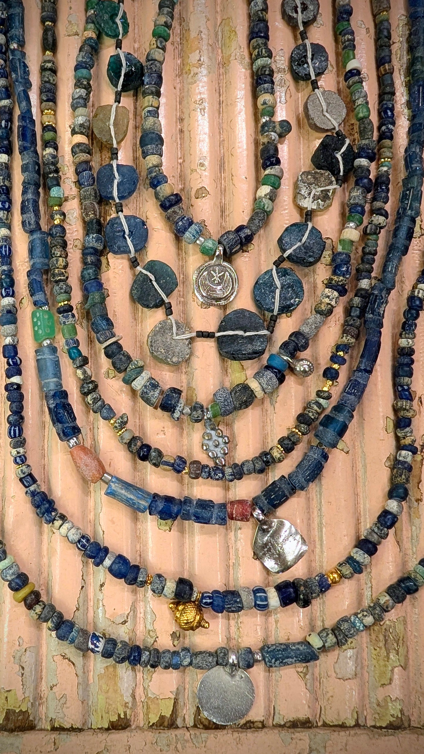 These antique beads are excavated in Mali and Afghanistan, they were traditionally buried under the threshold of the home and places of worship for protection and good luck. Blue glass was highly prized.

The Malian beads are Roman period, and the Afghan ones are typically at least 200-300 years old.

We have threaded them up with antique Saharan and Indian silver amulets and beads too.

The patina on the beads is beautiful, they are aged and frosted by generations of wear and being in the ground like sea g