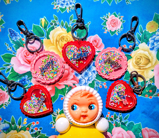 KITSCH, KITSCH, KITSCH Happy and Love keyrings with shaking rainbow sprinkles!!!

Kitschy keyring to help stop you from losing your keys!?!?! 

12.5cm including ring. 

Plastic and metal and sprinkles

 Acorn and Wills keyring