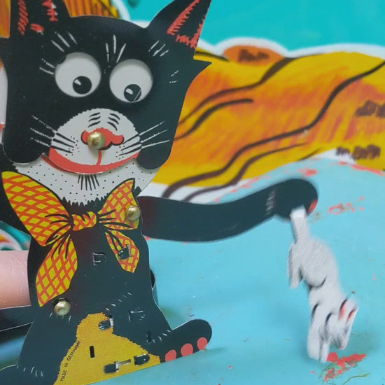 This cheeky tin toy cat is having such a time with a rabbit he has caught.