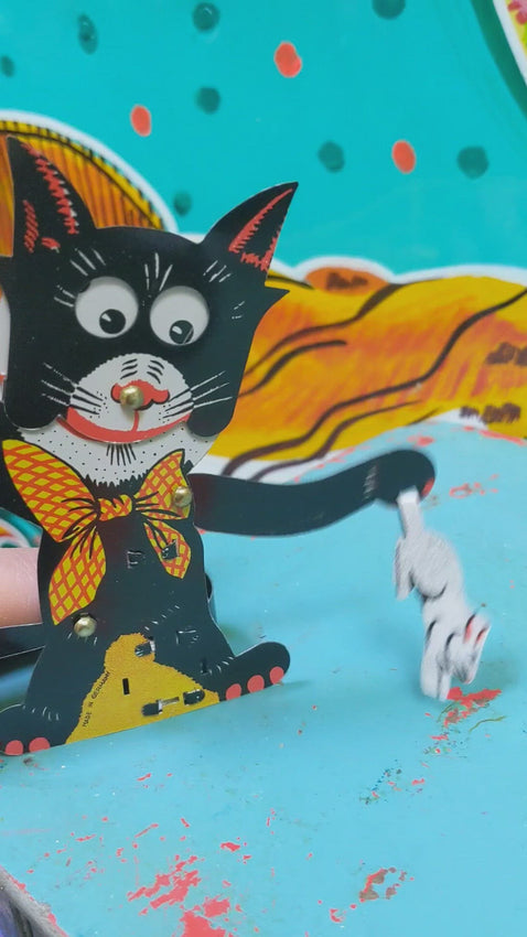 This cheeky tin toy cat is having such a time with a rabbit he has caught.