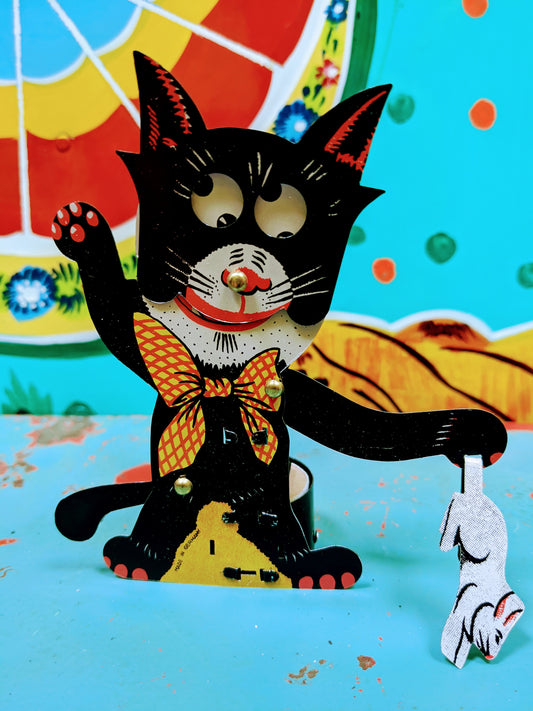 This cheeky tin toy cat is having such a time with a rabbit he has caught.